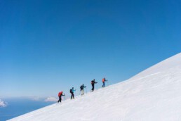 fünf Personen wandern einen verschneiten Berg hinauf / Pistentouren - Die sanfte Revolution
